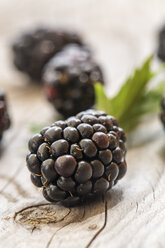 Blackberries and a leaf on wooden table, close-up - SARF000724