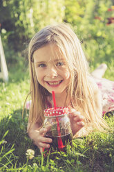 Portrait of smiling little girl lying on a meadow in the garden - SARF000727