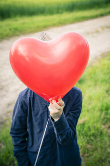 Little boy hiding his face behind a red heart-shaped balloon - SARF000732