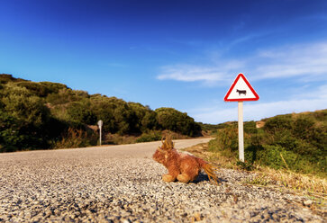 Spanien, Balearen, Menorca, Verkehrsschild an einer Straße mit Stofftier - SMAF000224