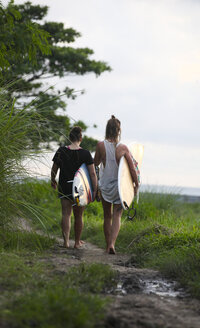 Indonesia, Bali, Canggu, two women with surfboards walking along footpath - FAF000050