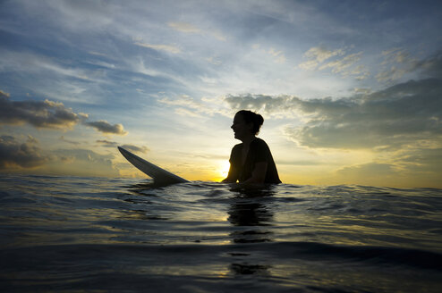 Indonesien, Bali, Canggu, Silhouette einer jungen Frau mit Surfbrett in der Dämmerung - FAF000052