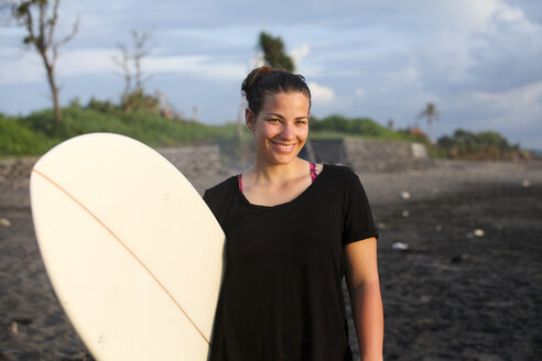 Indonesia, Bali, Canggu, portrait of happy young woman with surfboard on the beach - FAF000055