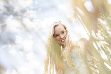 Porträt einer lächelnden jungen Frau in einem Roggenfeld - DRF000948