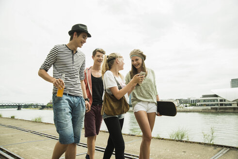 Group of friends walking at the riverside - UUF001389