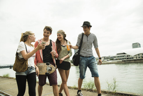 Group of friends walking at the riverside - UUF001390