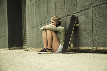 Teenager-Mädchen mit Skateboard an Betonwand - UUF001392