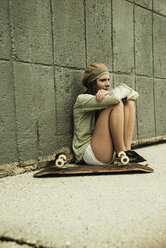 Teenager-Mädchen mit Skateboard an Betonwand - UUF001393