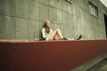 Teenage girl with skateboard at concrete wall - UUF001394