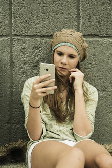 Teenager-Mädchen mit Handy an Betonwand - UUF001395