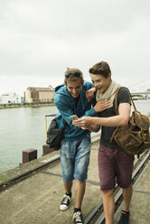 Two happy friends with cell phone by the riverside - UUF001402