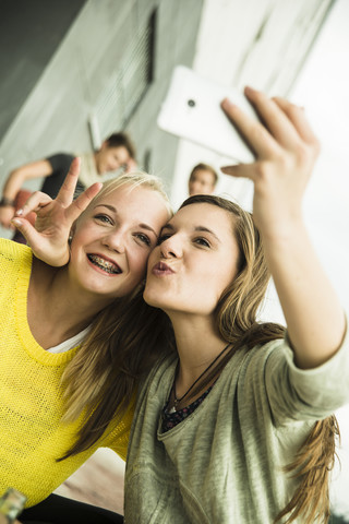 Zwei glückliche Mädchen im Teenageralter machen ein Selfie, lizenzfreies Stockfoto
