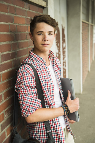 Jugendlicher lehnt sich an eine Backsteinmauer, lizenzfreies Stockfoto