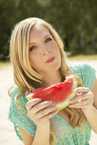 Porträt einer jungen Frau, die eine Scheibe Wassermelone isst, lizenzfreies Stockfoto