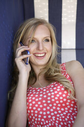 Porträt einer lächelnden jungen Frau, die mit einem Smartphone telefoniert - GDF000363
