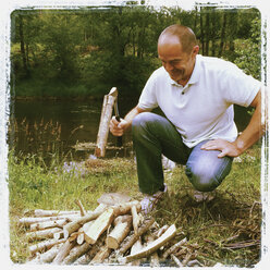 Belgien, Provinz Luxemburg, Die Ardennen, Mann in Bewegung spaltet Holz mit Axt, macht Feuerholz für Lagerfeuer und Grillen - GWF003013