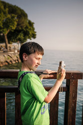 Italy, Veneto, Garda, Lake Garda, boy taking a photo - SBDF001046