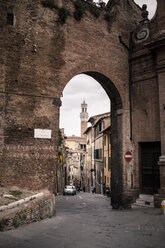 Italien, Toskana, Siena, Stadttor mit Turm des Palazzo Pubblico im Hintergrund - SBDF001038