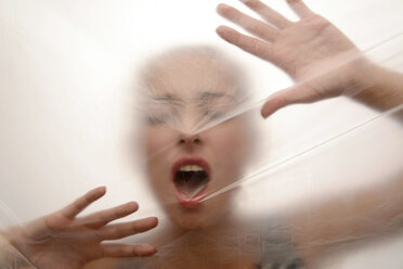 Young woman screaming behind foil - BFR000497