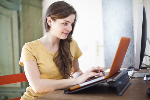 Junge Frau benutzt ihren Laptop zu Hause - FEXF000231
