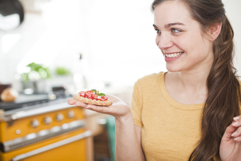 Junge Frau mit Erdbeertörtchen auf der Hand, lizenzfreies Stockfoto