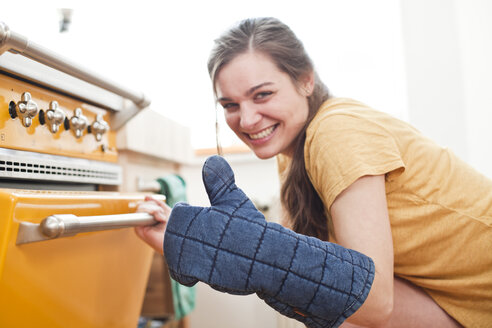 Portrait of smiling young woman in front of her oven - FEXF000184