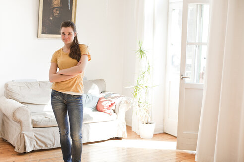 Junge Frau steht in ihrem Wohnzimmer - FEXF000192
