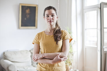 Portrait of young woman standing in her living room - FEXF000193