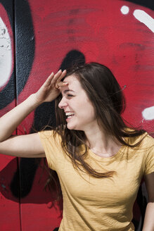 Portrait of smiling young woman standing in front of a graffiti - FEXF000206