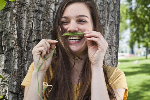 Porträt einer jungen Frau, die sich einen Stachel wie einen Schnurrbart ins Gesicht hält - FEXF000219