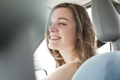 Porträt einer lächelnden jungen Frau, die in einem Auto sitzt - FEXF000225