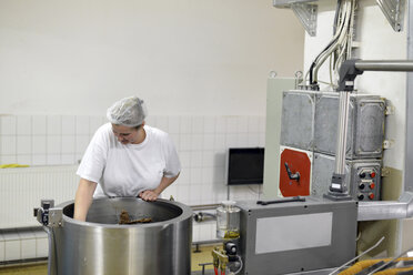 Deutschland, Sachsen-Anhalt, Frau rührt Schokoladenmischung in einem Kessel in einer Backfabrik - LYF000229