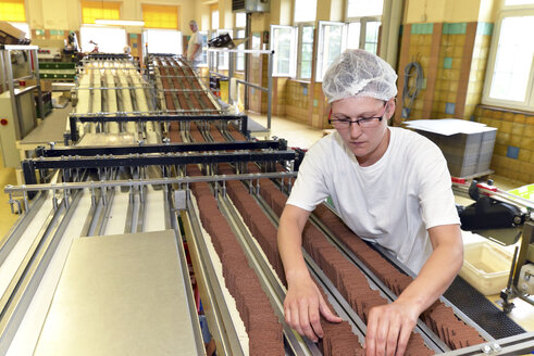 Germany, Saxony-Anhalt, woman working at production line in a baking factory - LYF000242