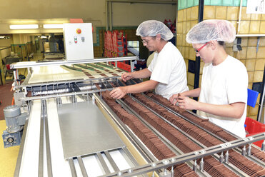 Deutschland, Sachsen-Anhalt, zwei Frauen bei der Arbeit am Fließband in einer Backfabrik - LYF000266
