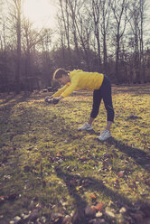 Germany, Hesse, Lampertheim, Woman doing sports with a branch in forest - UUF001491