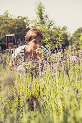 Ältere Frau riecht an Lavendel im Garten - UUF001471