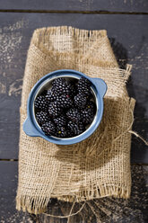 Bowl of blackberries, Rubus sectio Rubus, on jute and dark wood, elevated view - MAEF008818