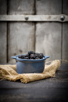 Schale mit Brombeeren, Rubus sectio Rubus, auf Jute und dunklem Holz vor einer Holzwand - MAEF008819