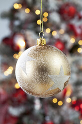 Golden Christmas bauble with white stars hanging in front of blurred flares - CSF022034