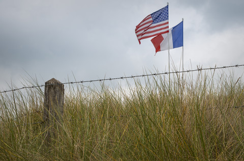 Frankreich, Basse-Normandie, Manche, Sainte Marie du Mont, Utah Beach, Stacheldrahtzaun und französische und amerikanische Flagge, lizenzfreies Stockfoto