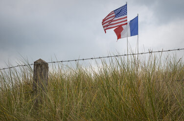 France, Lower Normandy, Manche, Sainte Marie du Mont, Utah Beach, Barbed wire fence and French and US flag - MKF000046