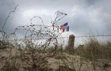 France, Lower Normandy, Manche, Sainte Marie du Mont, Utah Beach, Barbed wire fence and French and US flag - MKFF000047
