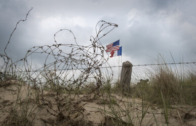 Frankreich, Basse-Normandie, Manche, Sainte Marie du Mont, Utah Beach, Stacheldrahtzaun und französische und amerikanische Flagge - MKFF000047