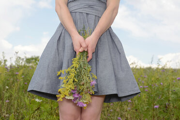 Young woman on wildflower meadow holding flowers - BFRF000475