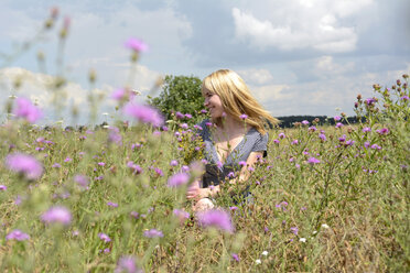 Glückliche junge Frau auf einer Wildblumenwiese - BFRF000477