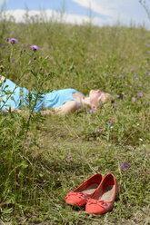 Junge Frau in Wildblumenwiese liegend - BFRF000479