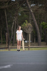 Frankreich, Aquitanien, Seignosse, Frau wartet mit ihrem Longboard - FAF000035