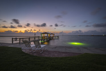 USA, Texas, Rockport, Zwei leere Liegestühle an der Strandpromenade, hölzerner Fischersteg bei Sonnenaufgang - ABAF001438