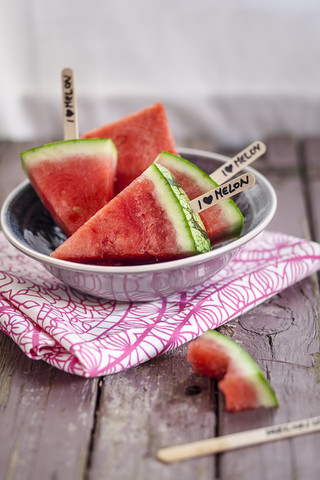 Schale mit Melonen-Eis am Stiel und ein angebissenes Eis auf Holz, lizenzfreies Stockfoto