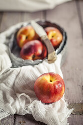 Bowl of nectarines and a knife on cloth and wood - SBDF001118